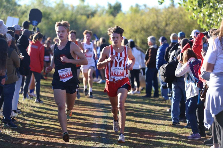 With the crowd along both sides of the course, Kayden Chaparro runs alongside another runner in the state meet. Chaparro finished 18th overall and ran a career-best 16:31 5k time.