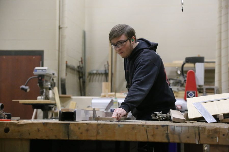 Senior Joshua Bowen cuts planks down to a precise measurement with the table saw for his personal project.