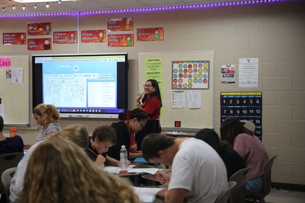 Smiling and lecturing, Spanish 2 teacher Vianca Ramos helps her students during a listening activity where students matched actions to the subjects performing the actions. A teacher plants the seeds of knowledge, sprinkles them with love, and patiently nurtures their growth to produce tomorrows dreams, Ramos said.