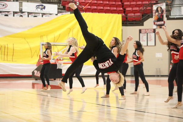 Flinging himself into the air, senior Keaton Cox performs a quick show with the pom team to pump up the south side of the gym before the talent show begins. Cox’s flip started with just a few spins in front of the team and was the ending move to the performance.